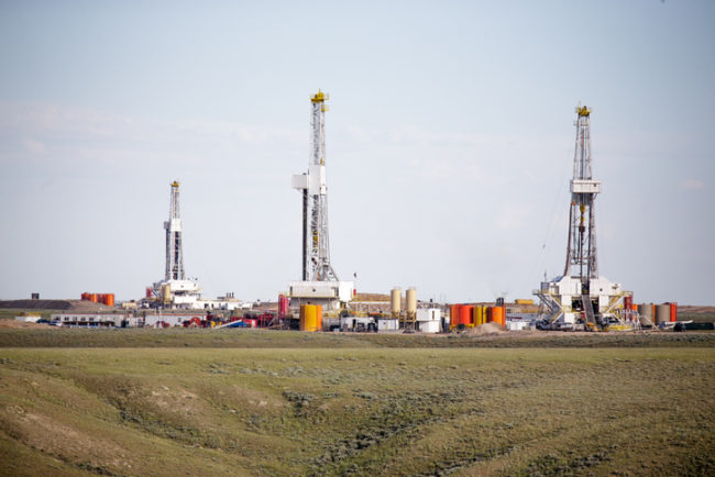Three hydro- fracking derricks drilling natural gas on a plain