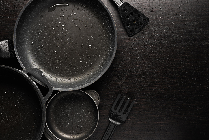 Black frying pans with a non-stick teflon coating on black background