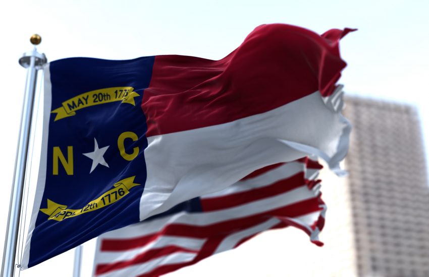 The flags of the North Carolina state and United States of America waving in the wind. Democracy and independence.