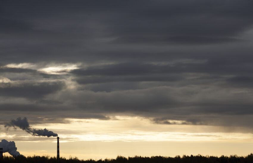 dark sky at sunset time, yellow color in the sky from the sun, pipes with smoke during operation and burning fuel - logs or coal